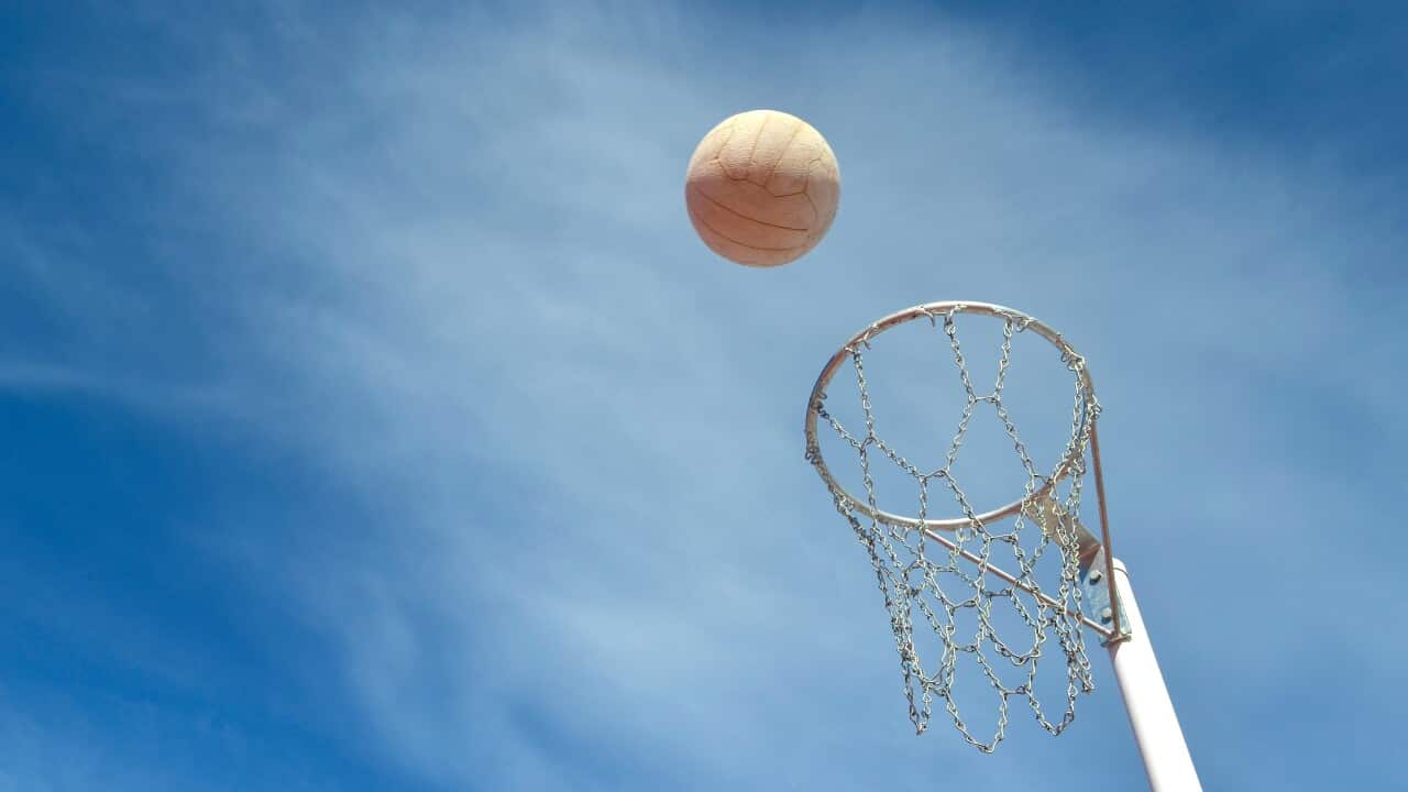 A netball being thrown into a hoop.