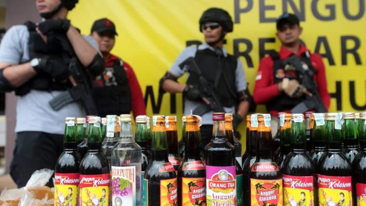 Police in Indonesia with bottles of bootleg alcohol