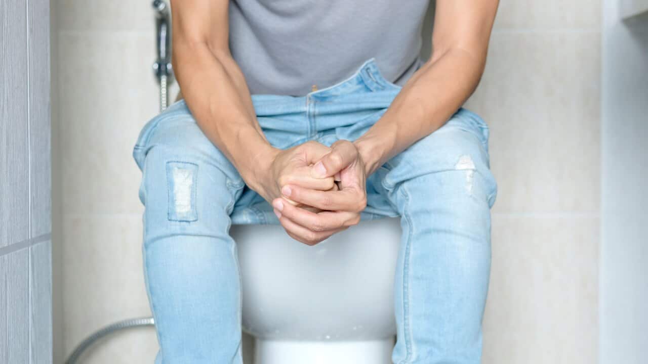 A man seated on a toilet.