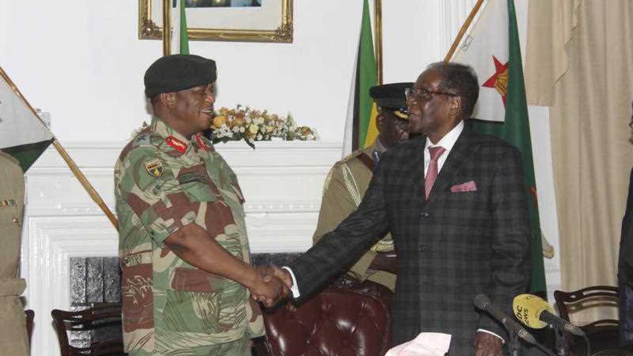 Zimbabwean President Robert Mugabe, right, shakes hands with Army General Constantino Chiwenga before delivering his speech during a live broadcast at State House in Harare, Sunday, Nov, 19, 2017.