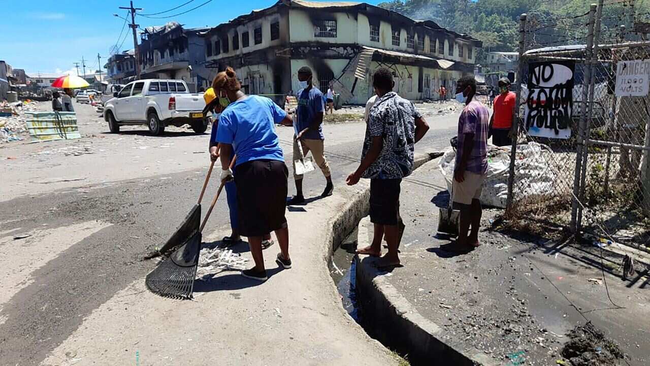 People clear debris from the streets in Honiara's Chinatown on 28 November, 2021 after riots roiled the capital.
