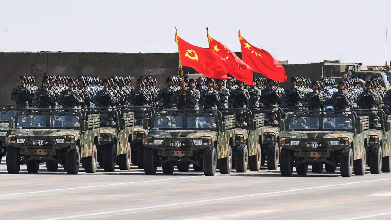 Chinese soldiers carry the flags of the Communist Party during a military parade.