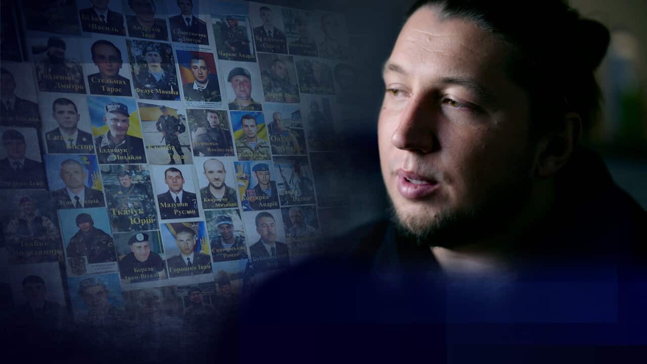 A man in front of photographs of soldiers who have been killed on the Ukraine frontline.