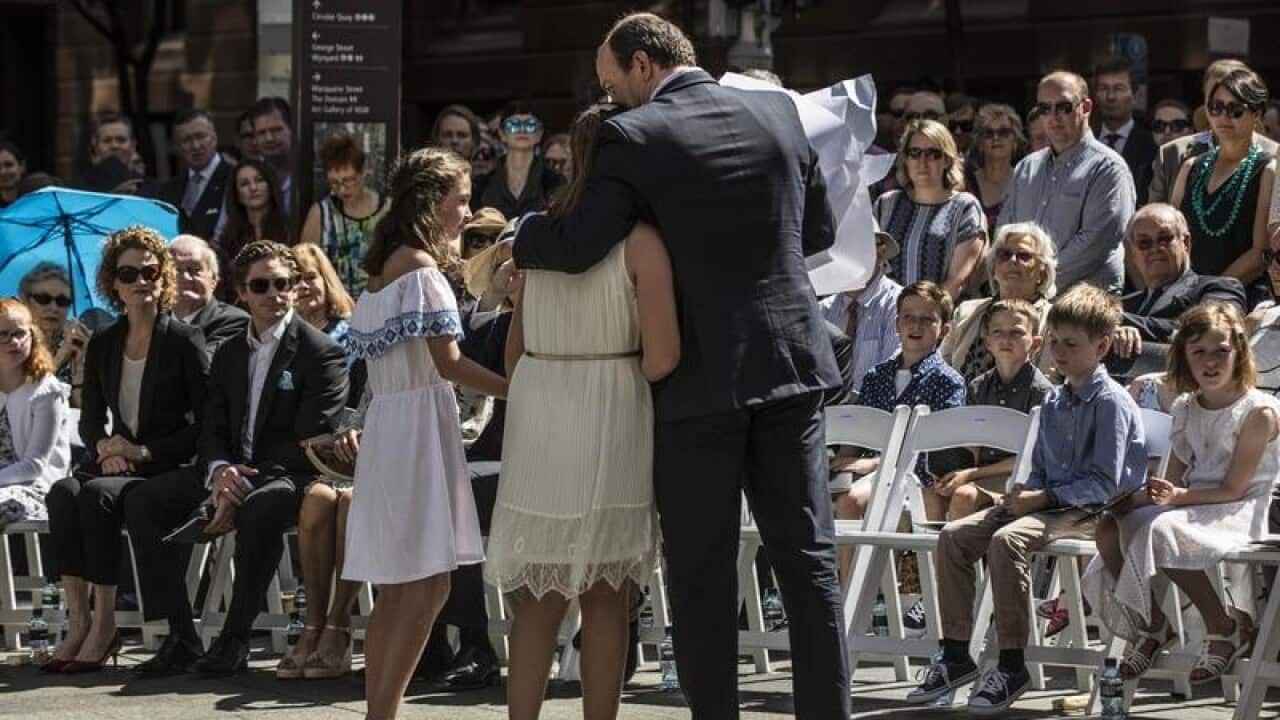 It was an emotional day for Katrina Dawsons's daughter Chloe (hugging her father) as a permanent tribute to victims of the Lindt Cafe siege is unveiled.