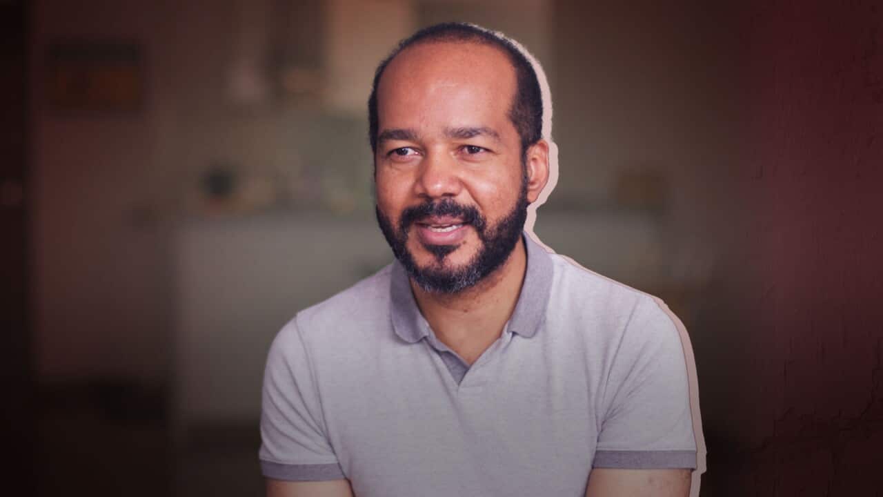 A man with a short beard wearing a grey polo shirt