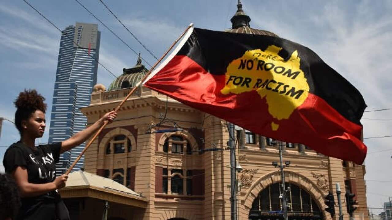A protester waves a flag during an "Invasion Day" rally on Australia Day in Melbourne on January 26, 2018. Tens of thousands of people marched across Australia on January 26 in an "Invasion Day" protest calling for a rethink of the national day they say i