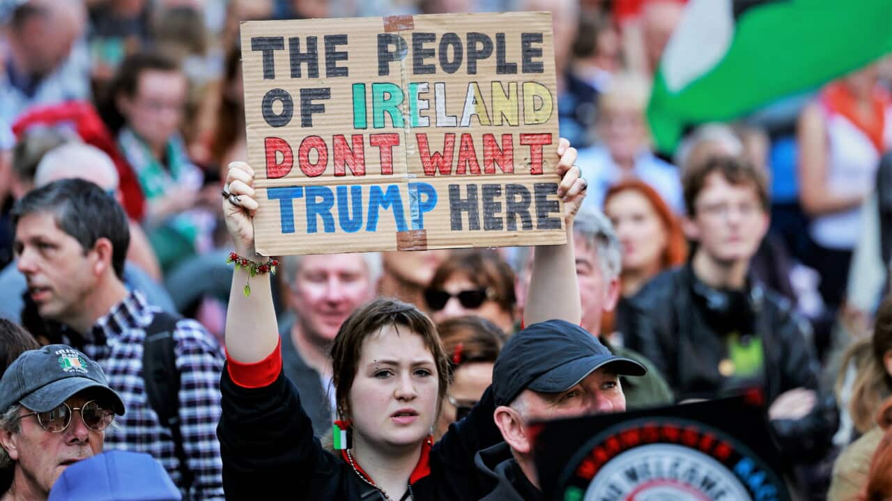 A protester in a crowded Dublin street holds up a cardboard sign reading "The people of Ireland don't want Trump here."