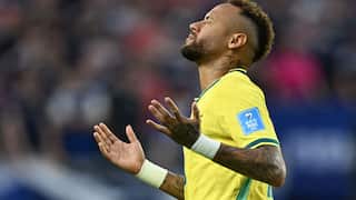 Neymar, wearing a yellow football shirt, holds his hands in front of him