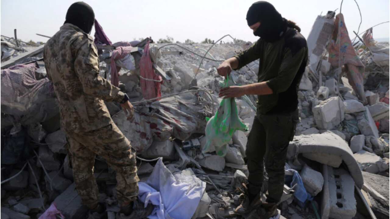 People look at a destroyed house in Idlib province after the US operation targeting Abu Bakr al-Baghdadi.
