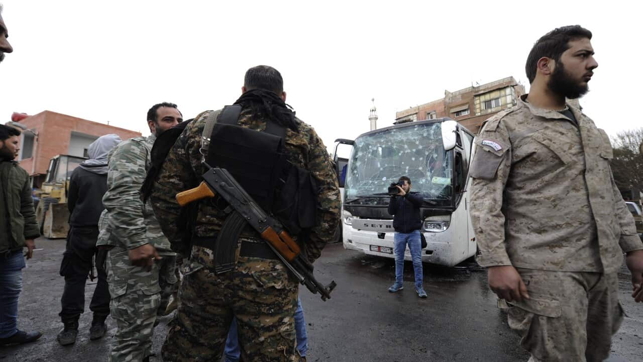 Syrian security officials stand next to a damaged bus at the site of bombing, in Damascus, Syria