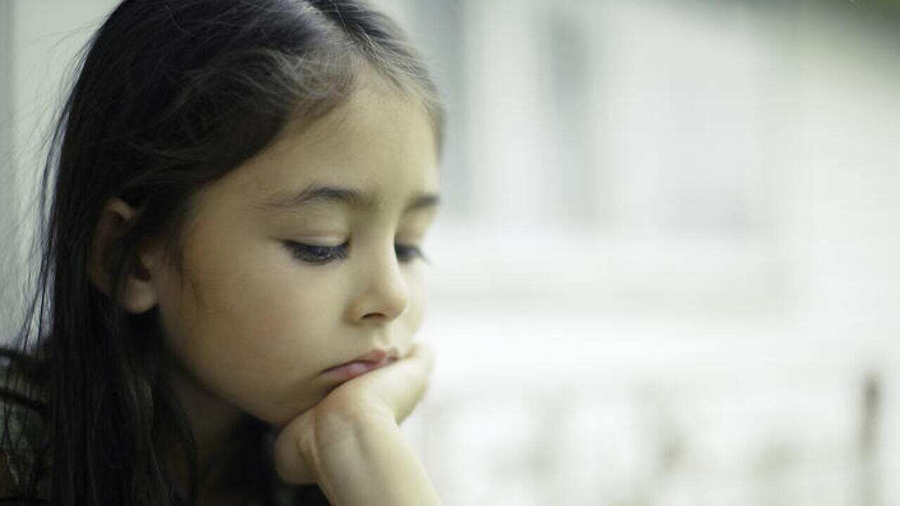 Girl by window with chin resting on hand