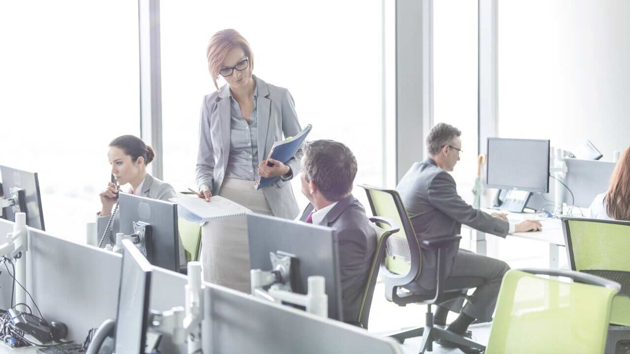 Business people working in open plan office with hot desks, but this close proximity will no longer take place between staff.