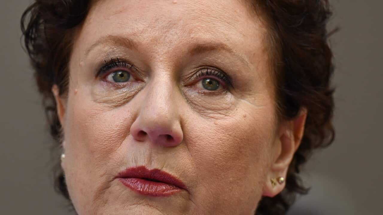 A woman with short brown hair, earrings and red lipstick.