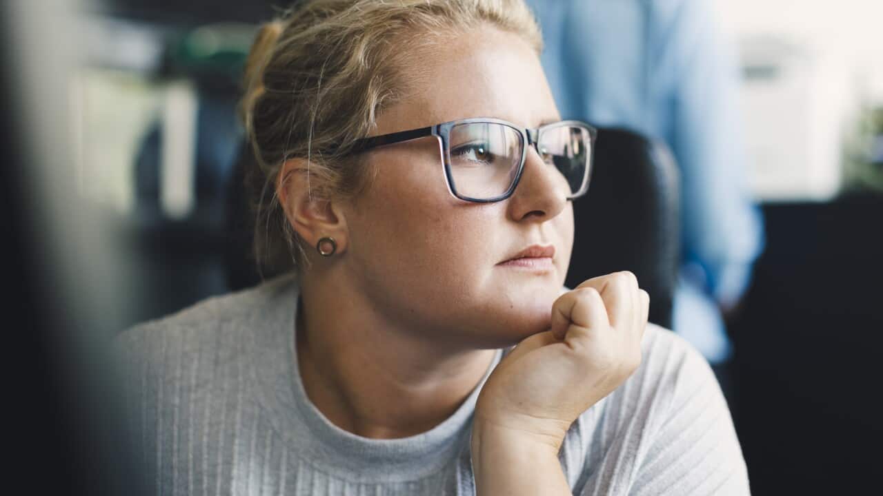 Office worker with hand on chin looking away.
