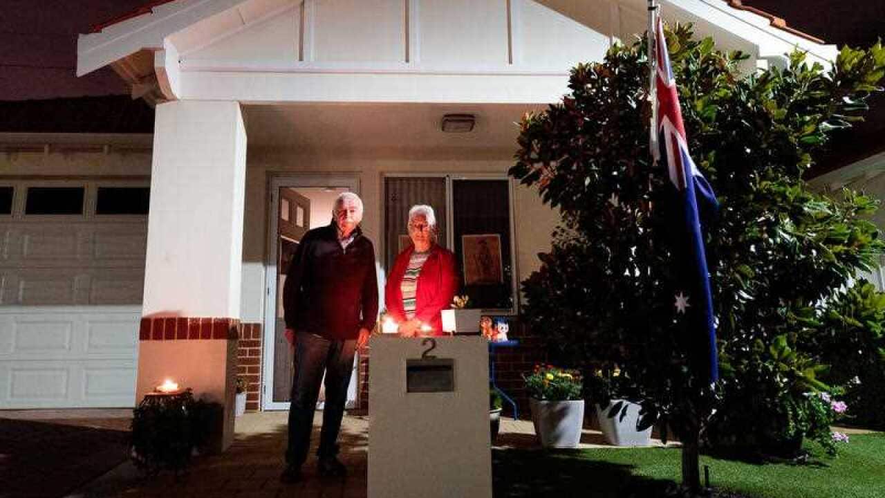 Jim Crockett and Suzanne, residents at a retirement village are seen outside their home at dawn on Anzac Day in Perth.