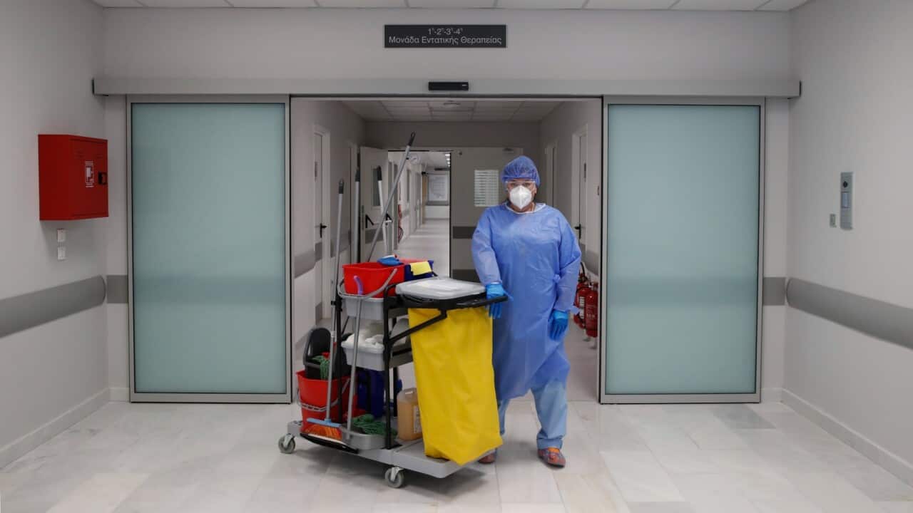 A cleaning worker poses outside the ICUs entrance of the Sotiria Thoracic Diseases Hospital in Athens, Monday, Jan. 18, 2021.