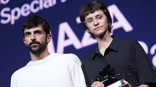 A man in a white t-shirt and a woman in a black shirt holding a trophy look on