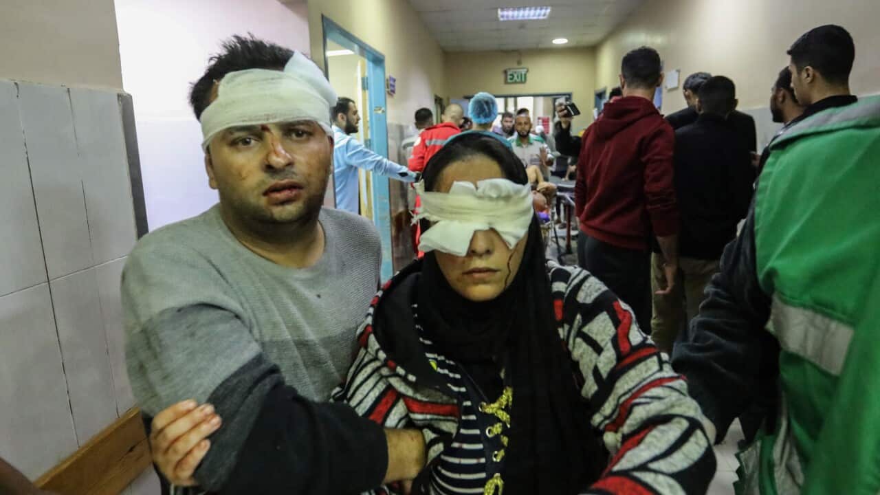 A man leading an injured woman in a hospital corridor
