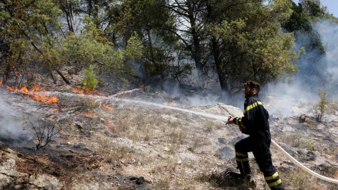 A Bosnian firefighter fights fire to protect a village from oncoming forest fire in the village of Trebizat, near the southern Bosnian town of Capljina