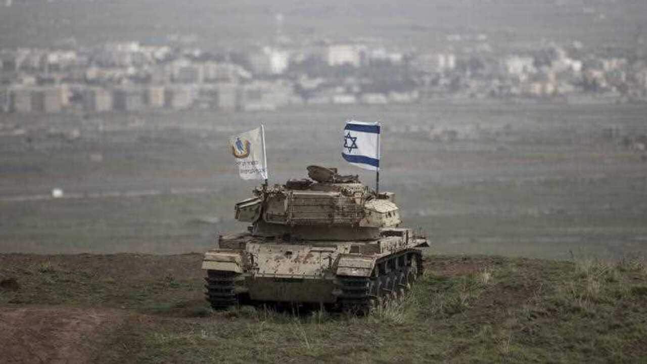 An Israeli flag is raised on an old Israeli tank from the remains of the Israeli-Syrian war in 1973 near the Syrian city of Quneitra in the Golan Heights