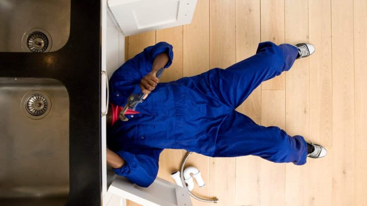 Plumber working under kitchen sink, overhead view