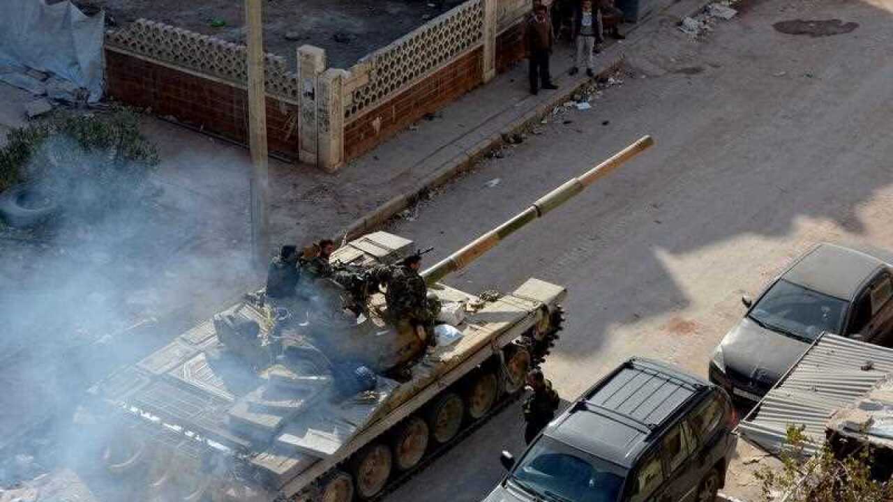 Syrian soldiers sit on their tank crossing Aleppo's western Minyan district, Aleppo, Syria
