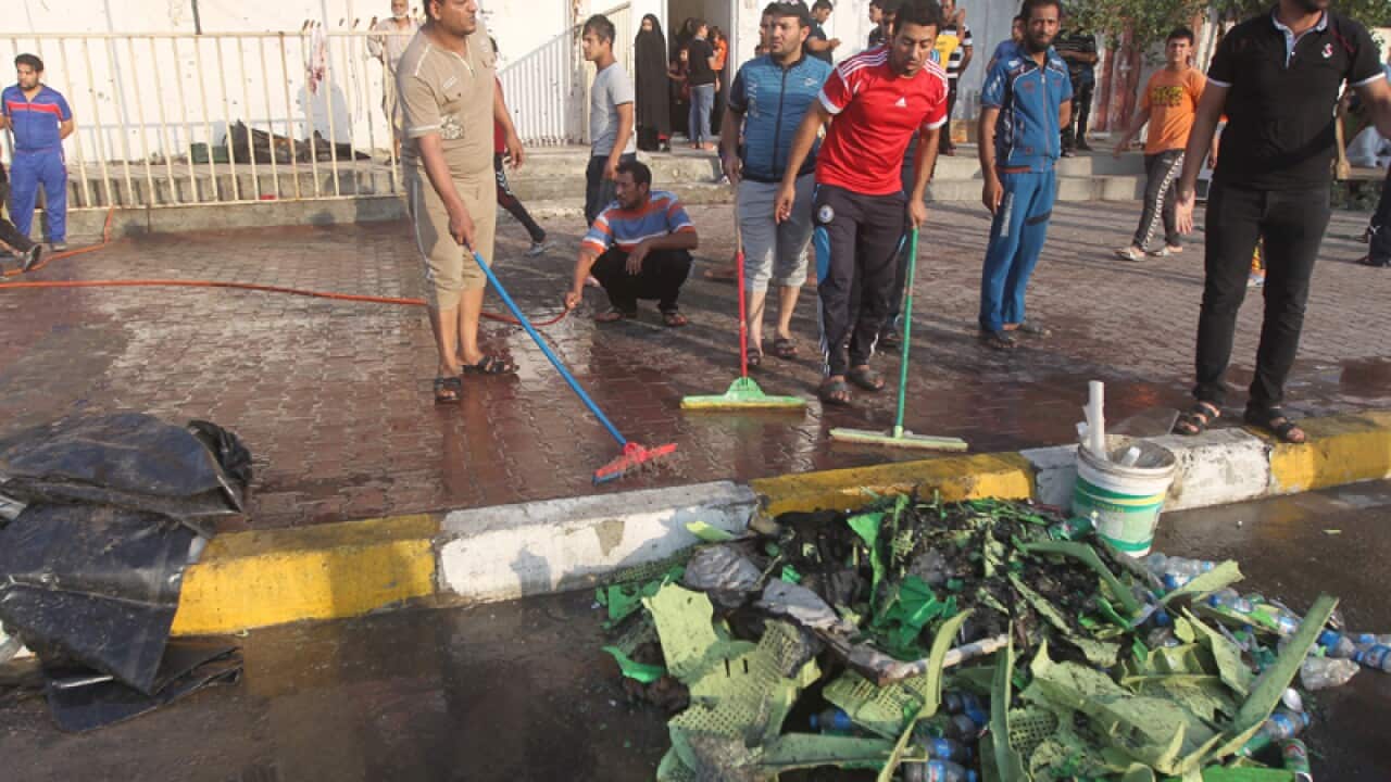 Iraqis clean the street after a suicide bombing attack in Sadr City