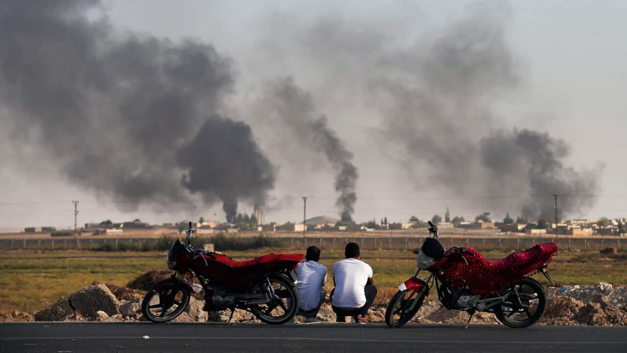 People in southeastern Turkey, at the border with Syria, watch smoke billowing inside Syria
