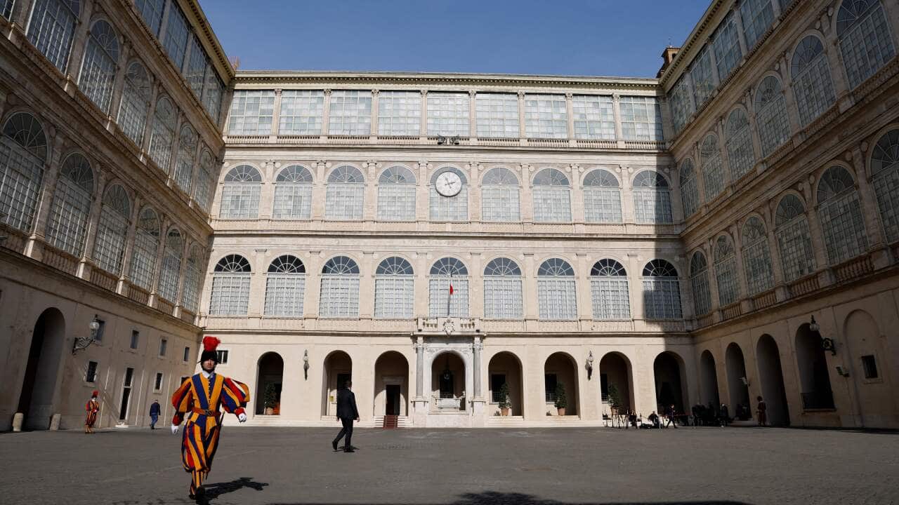 A member of the Swiss Guard walking through the Vatican's San Damasco courtyard