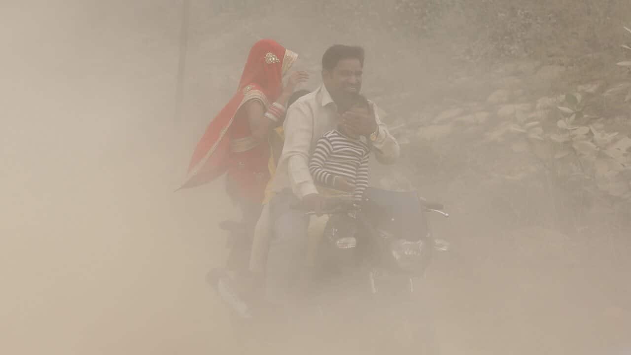 An Indian man and his family ride a bike during heavy dust and smog in New Delhi.
