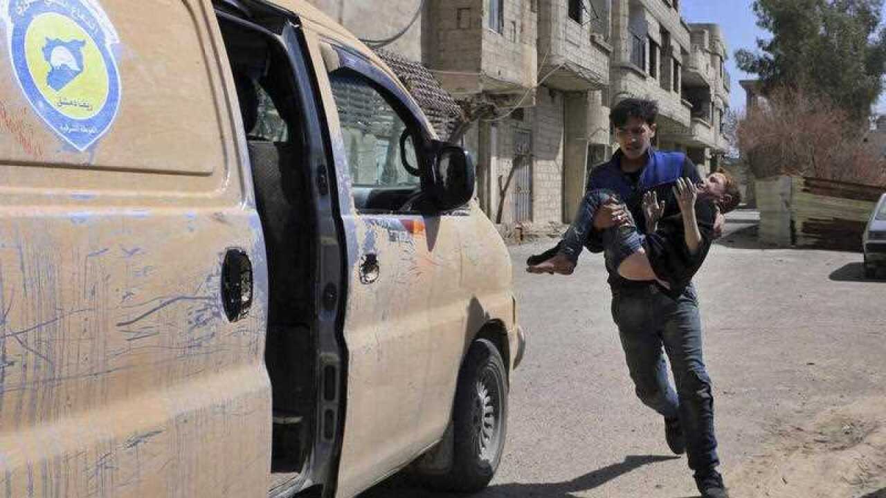 A member of the Syrian Civil Defense group carrying a boy who was wounded during airstrikes and shelling by Syrian government forces in Ghouta.
