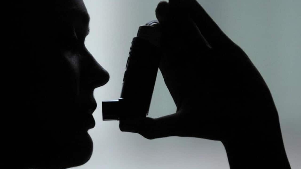 A stock photo of a person using an inhaler.