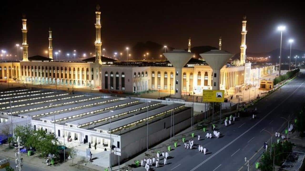 Haj pilgrims walking in front of a mosque the Arafat in Mecca ahead of Haj, Saudi Arabia