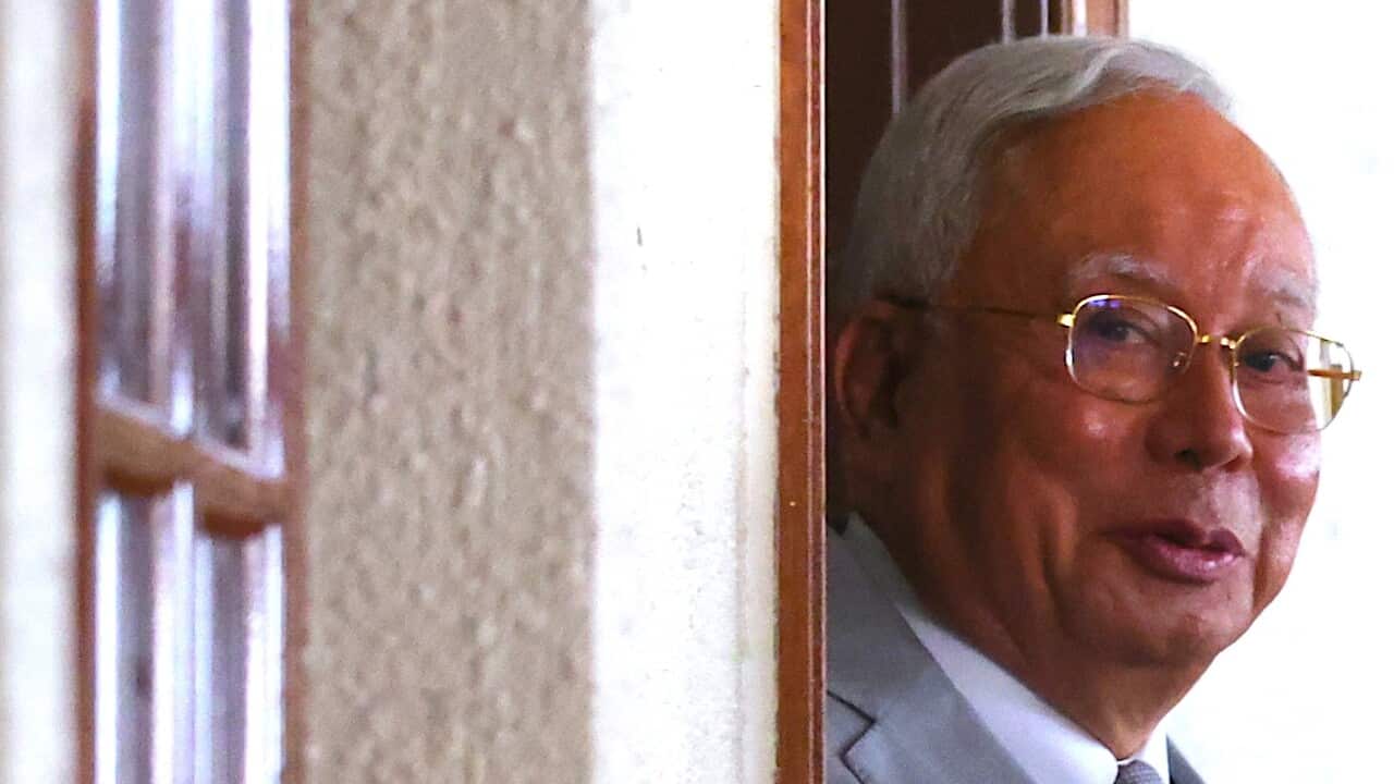 Najib Razak looking out a window or doorway.