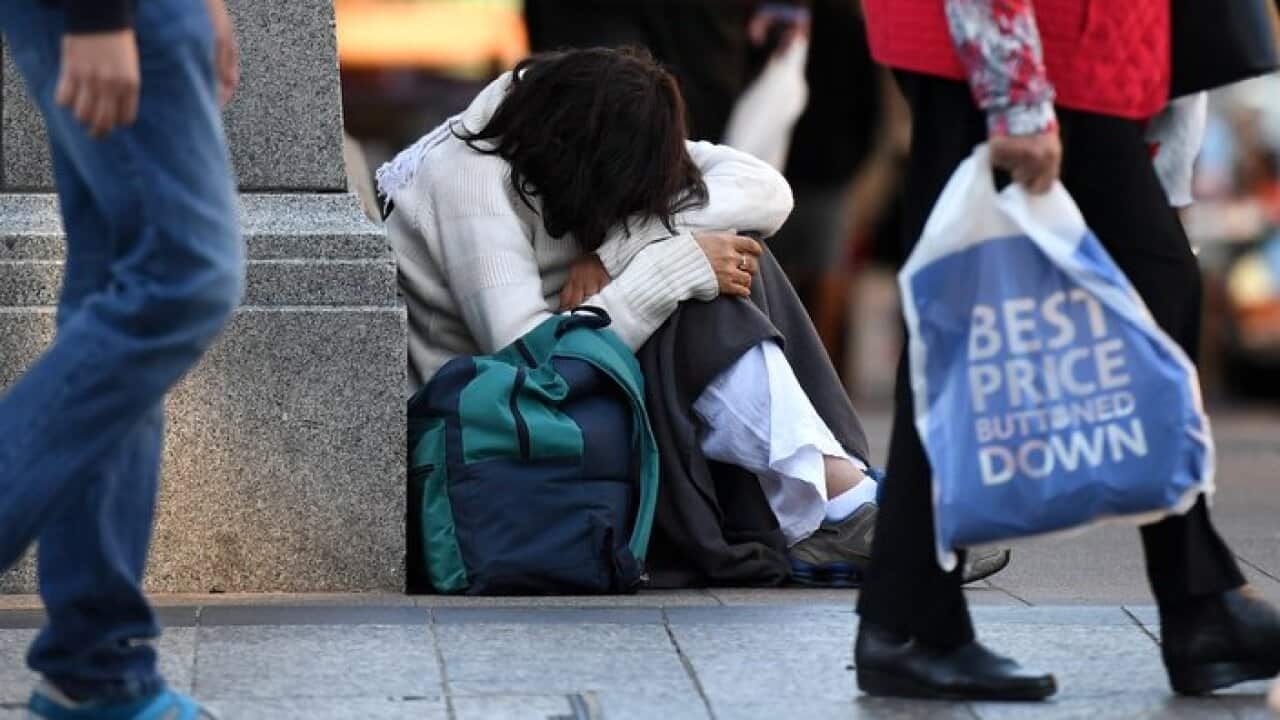 A homeless woman sits on a street corner in central Brisbane, Friday, June 9, 2017. (AAP Image/Dan Peled) NO ARCHIVING