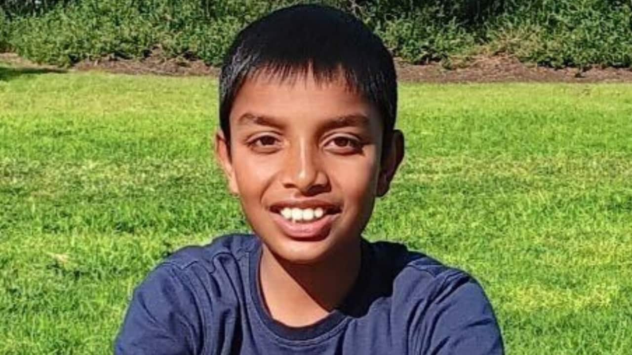 A boy in a blue shirt sitting on grass