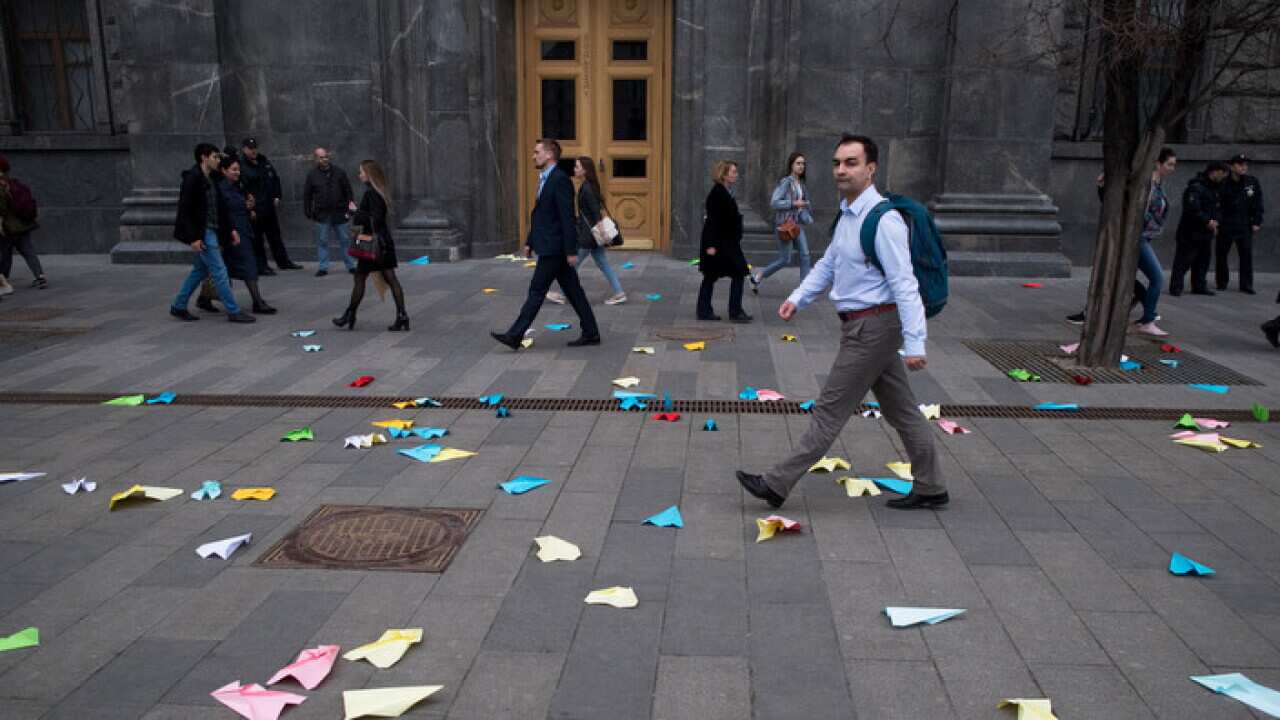 People walk past paper airplanes that were thrown by protesters in front of the Federal Security Service in Lubyanskaya Square in Moscow, Monday, April 16, 2018
