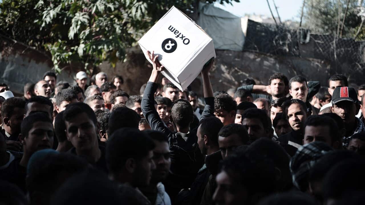 A Palestinian man carries a box of hygiene supplies outside an Oxfam warehouse in Gaza (Getty).jpg