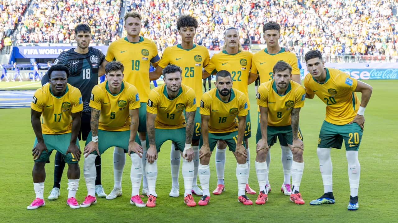 Australian football players in green and gold colours posing together on a football pitch