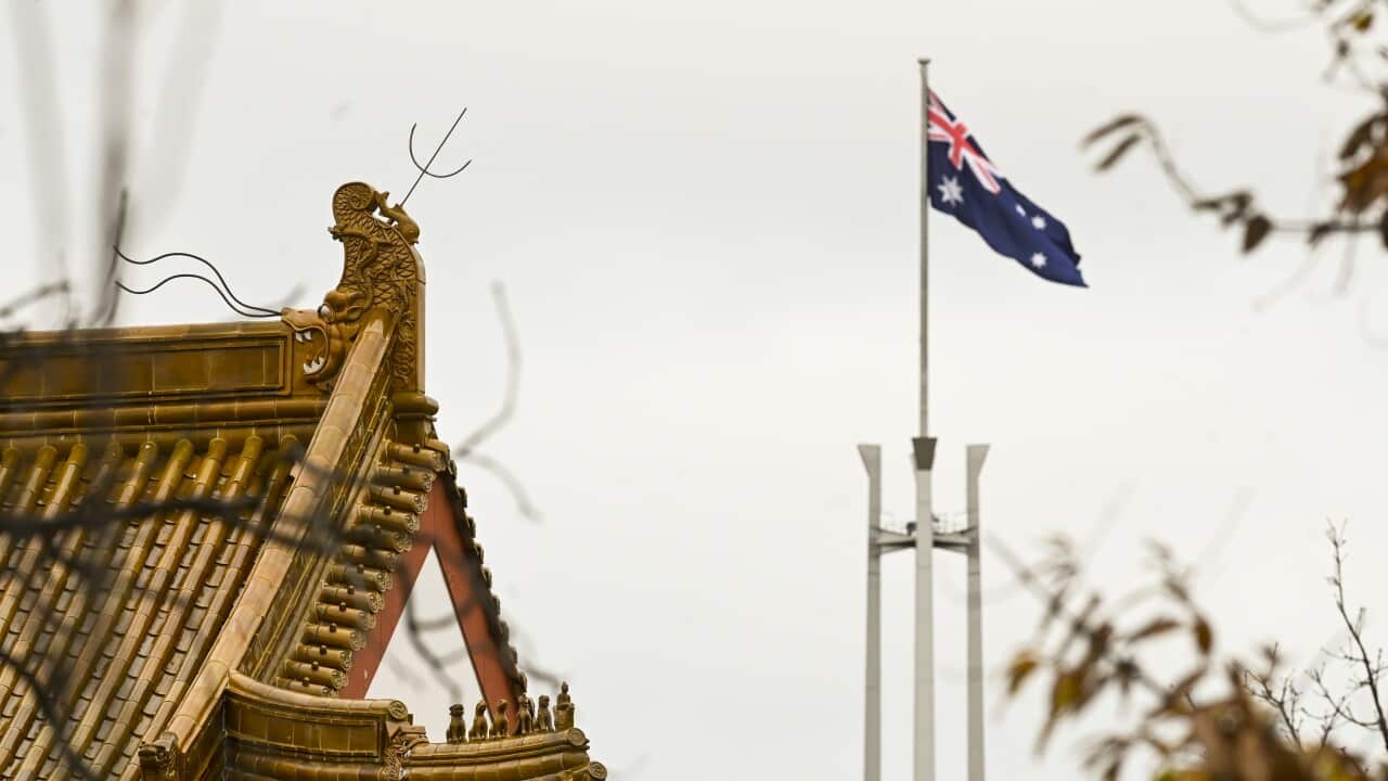 The flag pole of the Australian Parliament is seen behind the roofs of the Chinese Embassy in Canberra, Monday, June 29, 2020. (AAP Image/Lukas Coch) NO ARCHIVING