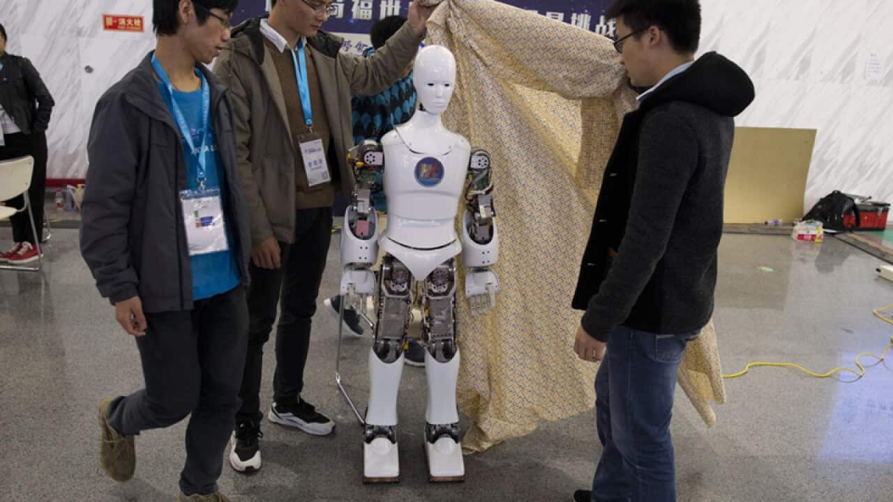 Chinese college students remove the cover from a robot