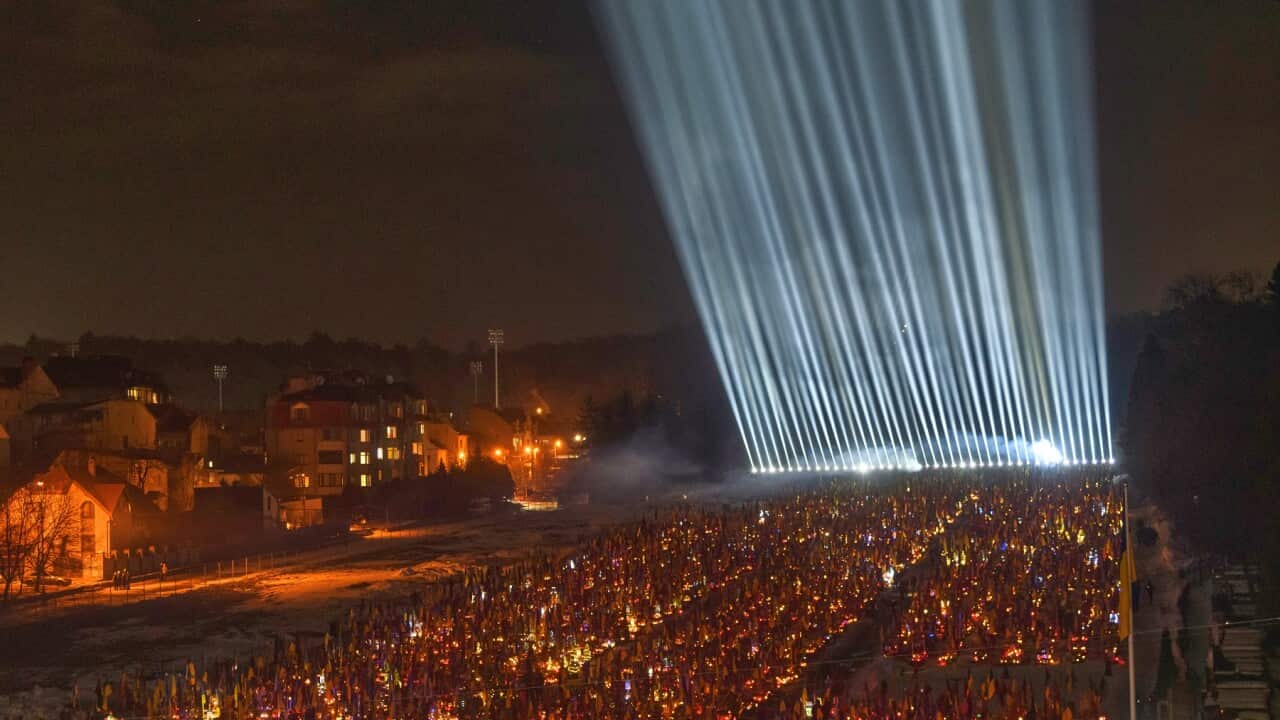 Floodlights shine over the graves of the fallen soldiers in Lviv as people lit candles on the eve of the fourth anniversary of Russia's full-scale invasion (AAP)