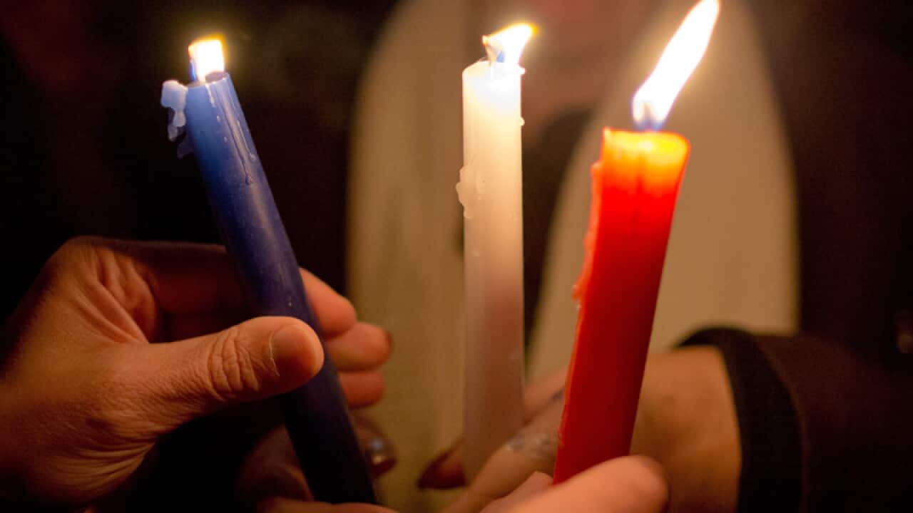 Attendants light candles of the French tri-colour