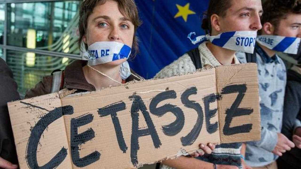 Demonstrators form a human chain and hold banners to protest against Comprehensive Economic and Trade Agreement (CETA), a trade deal between the EU and Canada