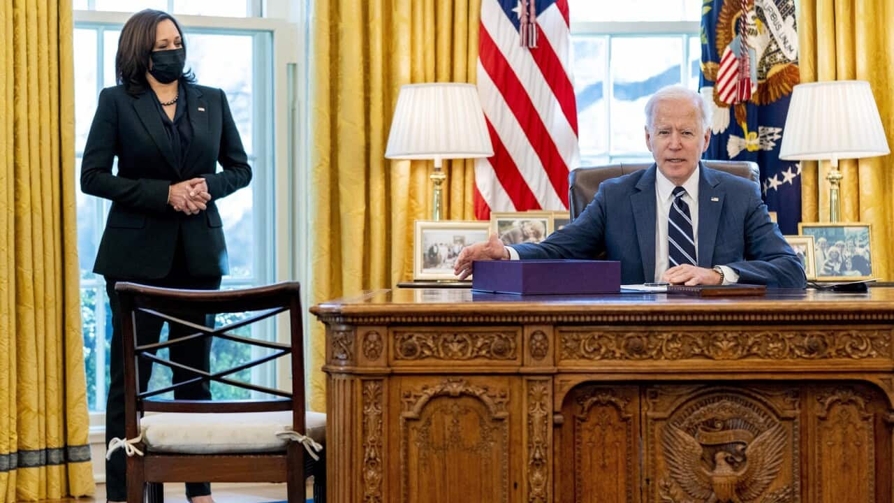 President Joe Biden, accompanied by Vice President Kamala Harris, looks up after signing the American Rescue Plan