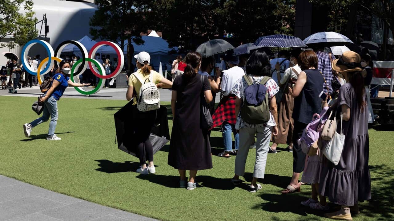 Visitors wait in a queue to take pictures with the Olympic Rings