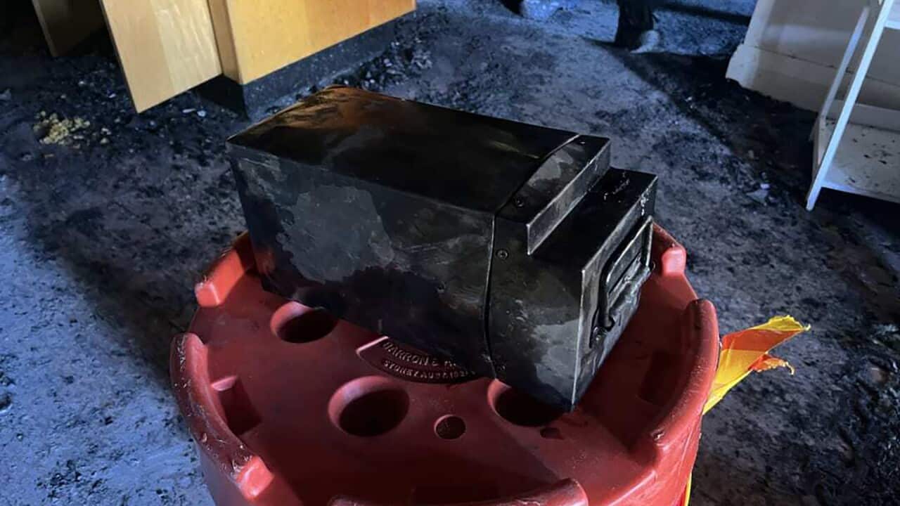 The black e-bike battery is left charging on the red round charging device on the floor