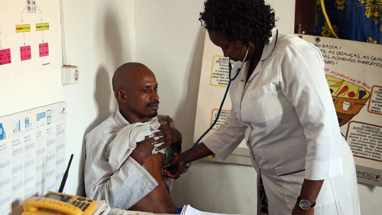 Guinea-Bissau's nurse Egidia Almeida (R) scans a Guinean citizen.