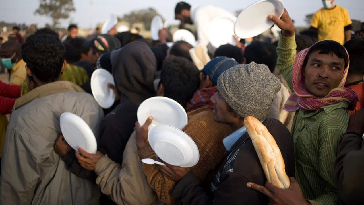 Refugees waited for food being handed out by the United Nations and Tunisian volunteers at a camp near the Libyan border.