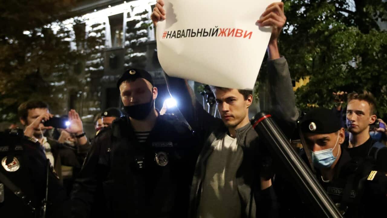 Police detain a protester with a sign reading Navalny, Live outside the Russian Federal Security Service building in Moscow.